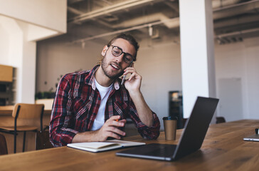 millennial student with netbook computer and education textbook calling via cellular app for discuss
