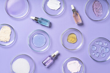 Wall Mural - Cosmetic products, scrub, face serum and gel in many petri dishes on a violet background. Cosmetics laboratory research concept.