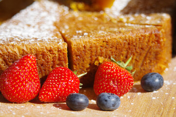 Poster - Closeup of berries near a cake on a wooden table