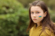 © Andriy Medvediuk - the face of a frightened girl, painted on her cheek in the yellow-blue colors of the Ukrainian flag, a request for help. Children ask for peace. High quality photo