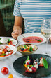 © sokorevaphoto - A man at a table in a restaurant tastes cold tomato soup. Tomato menu