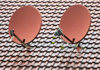 Red satellite dishes against the background of a wooden roof of a house