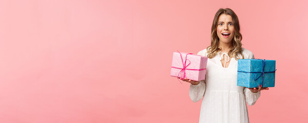 Wall Mural - Holidays, celebration and women concept. Portrait of surprised and impressed blond girl didnt expect receive so many presents, holding two wrapped gifts and smiling camera astonished