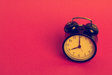 vintage old black alarm clock on pink background