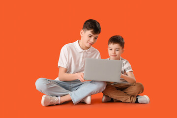 Portrait of cute brothers with laptop on color background