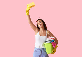 Wall Mural - Young woman with cleaning supplies on pink background