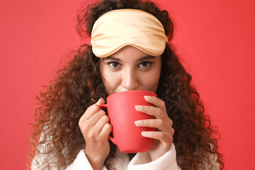 Sticker - Young African-American woman with sleeping mask drinking coffee on red background