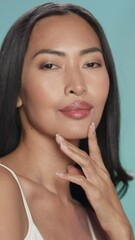 female beauty vertical portrait. beautiful asian happy brunette woman posing, touching her face with
