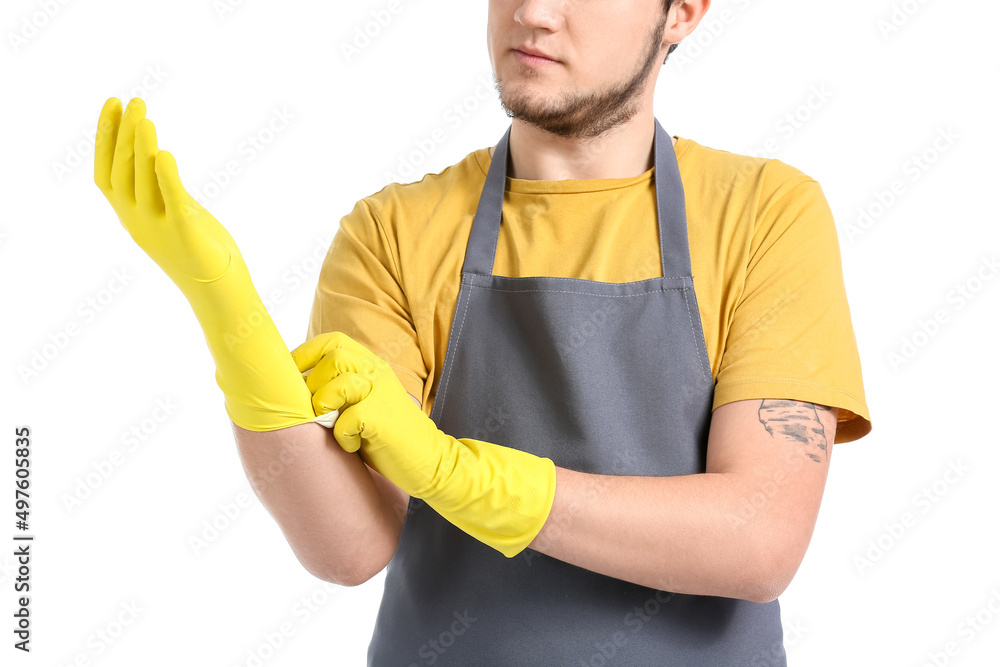 Young man putting on rubber gloves against white background