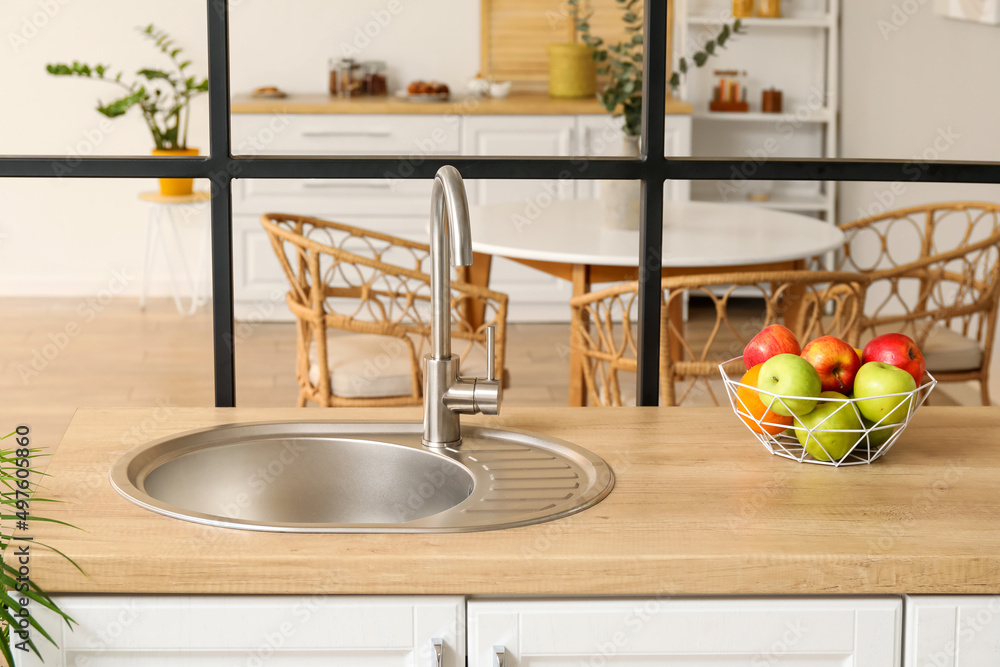 Silver sink and bowl with apples on kitchen counter