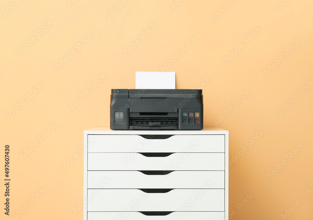 Modern printer on chest of drawers near color wall