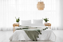 Comfortable Bed, Nightstands And Houseplants In Room