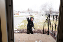 Boy Throws Snowballs At Front Door Of Home