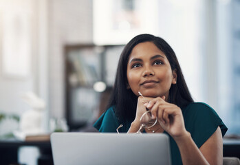 Sticker - Dreams are our realities in waiting. Shot of a young businesswoman looking thoughtful while working on a laptop in an office.