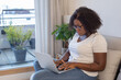 © Anna Berkut/Stocksy - black woman working on laptop computer at home, writing email
