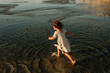© Erin Brant/Stocksy - Back view of young girl in dress on beach