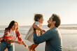 © Erin Brant/Stocksy - Happy father holding daughter at the beach
