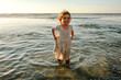 © Erin Brant/Stocksy - Smiling girl wading in the sea