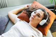 Sad Woman Laying On Sofa Listening To A Music