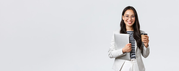 Business, finance and employment, female successful entrepreneurs concept. Confident good-looking businesswoman in glasses and suit drinking takeaway coffee and carry work laptop