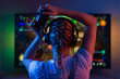 © Anton - A gamer or a streamer girl at home in a dark room with a gamepad playing with friends on the networks in video games. A young man sits in front of a monitor or TV.
