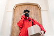 © Ezequiel Giménez/Stocksy - Serious delivery woman with parcel having phone call