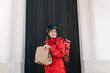 © Ezequiel Giménez/Stocksy - Smiling delivery lady with paper bag standing near door