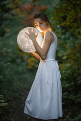 Wall Mural - beautiful attractive girl in a white dress in the autumn forest, hugs the moon, a mystery, a mysteri