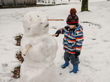 Small Boy Building A Snowman