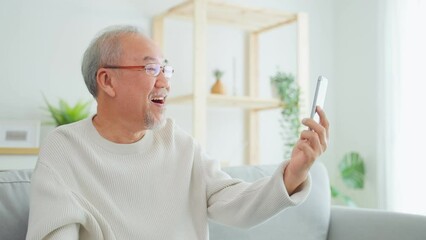 Wall Mural - Asian senior older man use mobile phone for video call in living room.