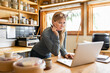 © Dylan Leeder/Stocksy - Cafe Owner On Laptop In Kitchen
