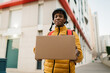 © Ezequiel Giménez/Stocksy - Smiling black delivery man giving parcel to camera