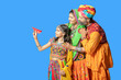 Happy indian daughter with her parent wearing colorful traditional outfits holding flying paper airplane against blue background, Rajasthani family dreams for their child. copy space.