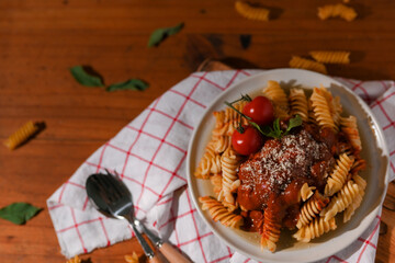 Wall Mural - Top view, Homemade fusilli pasta with tomato sauce on a wood dining table.