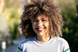 © Albert Martinez/Stocksy - Content curly haired woman in summer park