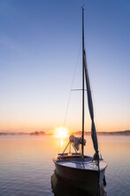 Dinghy Sailboat On Freshwater Lake At Sunrise