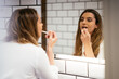 © Manu Padilla/Stocksy - Woman applying makeup and looking in mirror