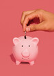 © Kate Perry/Stocksy - Hand dropping coin in piggy bank