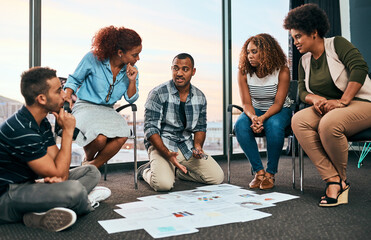 Sticker - Alright where should we start. Shot of a group of focussed young coworkers working together and brainstorming while being seated on the floor of the office at work during the day.