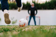 © Ezequiel Giménez/Stocksy - Kid playing football with father on green grass