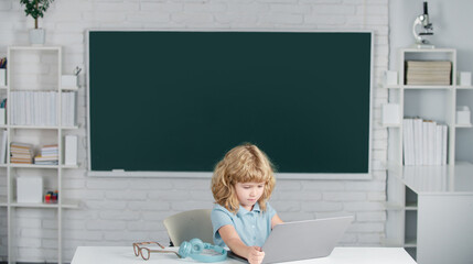 Fototapete - Boy student learning online in class. Kid study online video call with zoom. Pupil child learn english language online with laptop at school.
