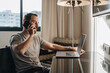 © Daniel Gonzalez/Stocksy - Male hotel guest working on laptop in room
