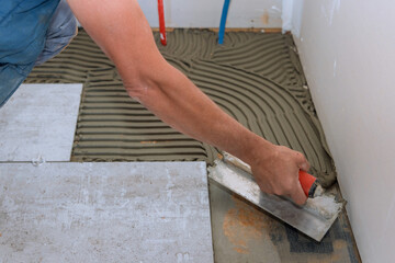 Canvas Print - Man making using adhesive cement base the ceramic tile flooring