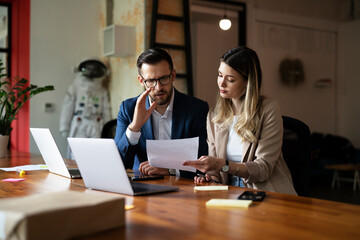 Wall Mural - Colleagues drinking coffee in office. Businesswoman and businessman discussing work in office..