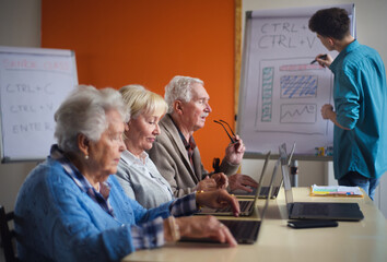 Sticker - Senior group in retirement home with young instructor learning together in computer class
