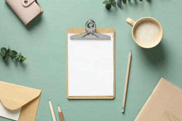 Wall Mural - Aesthetic minimal office desk table with clipboard mockup, coffee cup, stationery and eucalyptus leaves on green background. Flat lay, top view.