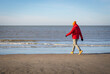 Zima nad morzem, ciepło ubrany mężczyzna spaceruje nad brzegiem morza.