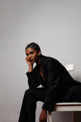 Vertical portrait of African young woman with long braids wears dark suite.