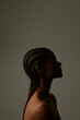 © face_reader_img - Vertical side portrait of African young woman with braids posing on dark wall.
