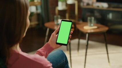 Aufkleber - Feminine Hand Holding a Smartphone with Green Screen Mock Up Display. Female is Relaxing at Home, Watching Videos and Reading Social Media Posts on Mobile Device. Close Up Over the Shoulder Footage.